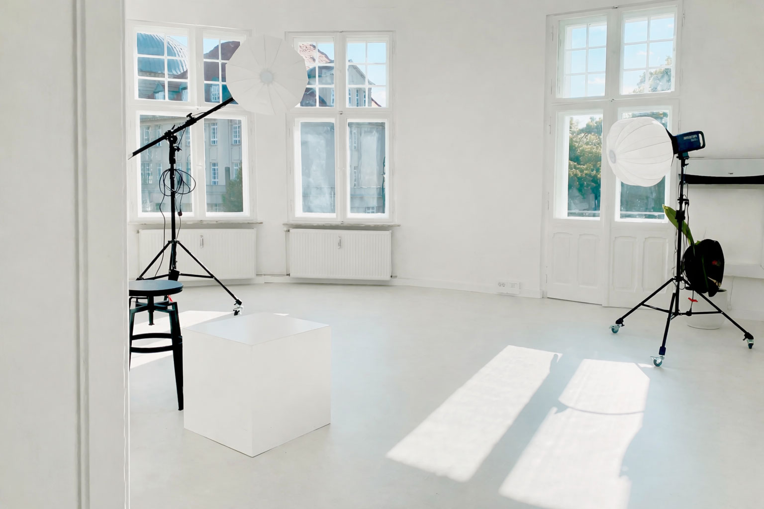 Helles Fotostudio mit großen Fenstern, ausgestattet mit professionellen Softboxen und modernem Equipment für kreative Projekte.