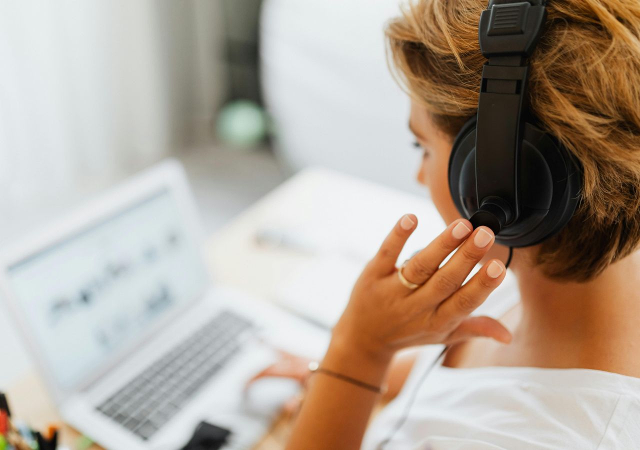 Frau mit Kopfhörern arbeitet an einem Laptop, modernes Homeoffice mit Fokus auf konzentrierte digitale Arbeit.
