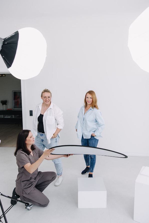 Fotostudio-Szene mit drei Frauen, professionelles Set mit Softboxen und Reflektor für ein Porträtshooting.