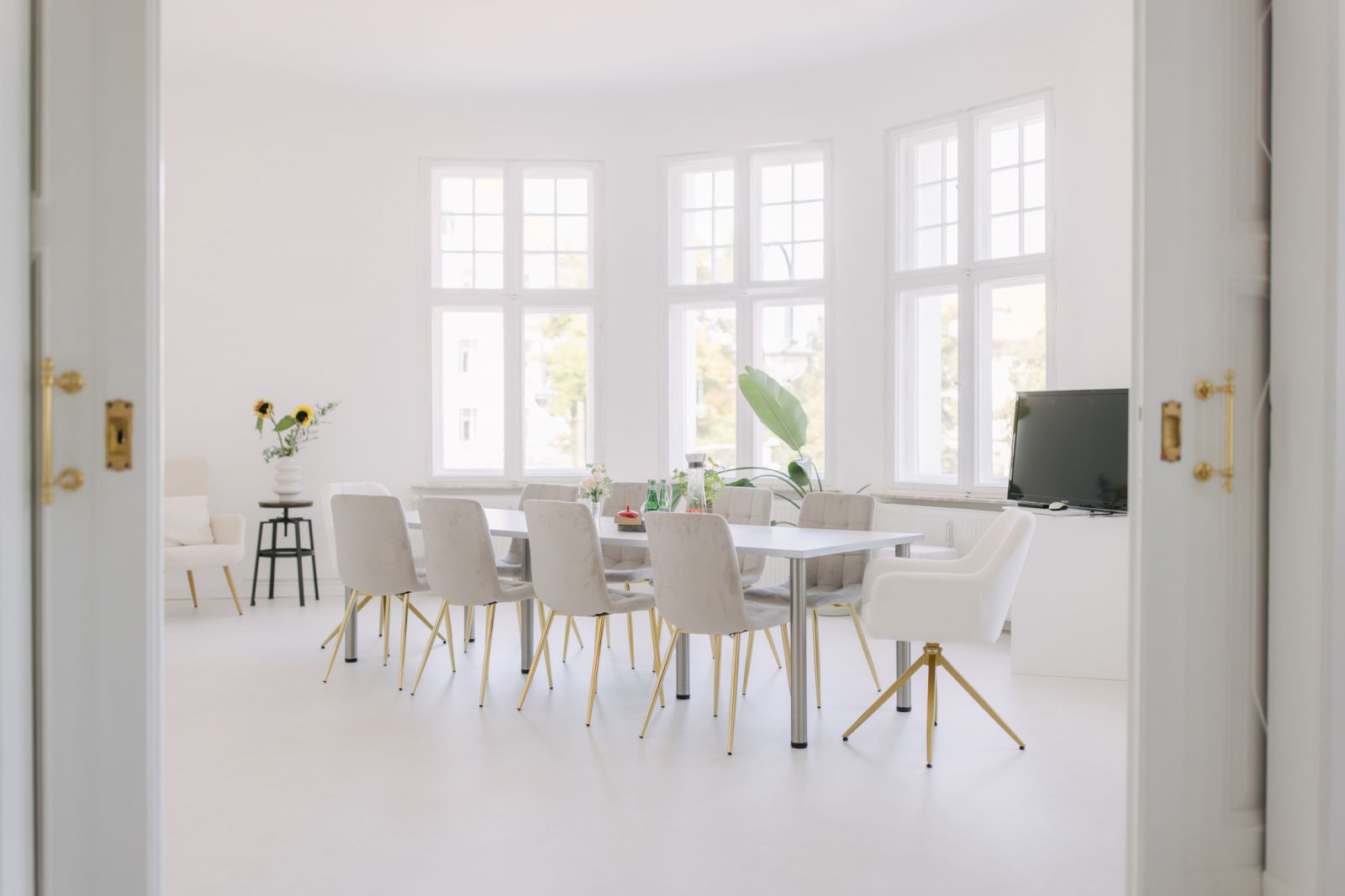 Heller Konferenzraum mit großem Tisch, stilvollen Stühlen, Fenstern und Dekoration, ideal für Meetings oder Events.