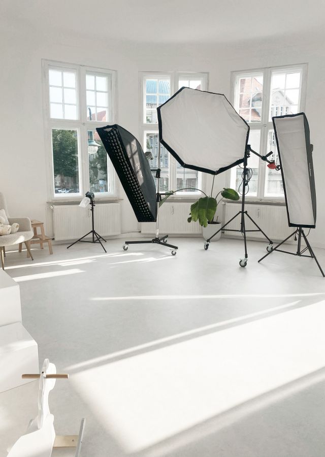 Helles Fotostudio mit großen Fenstern, Softboxen, Pflanzen und minimalistischem Setup für kreative Foto- und Videoproduktionen.