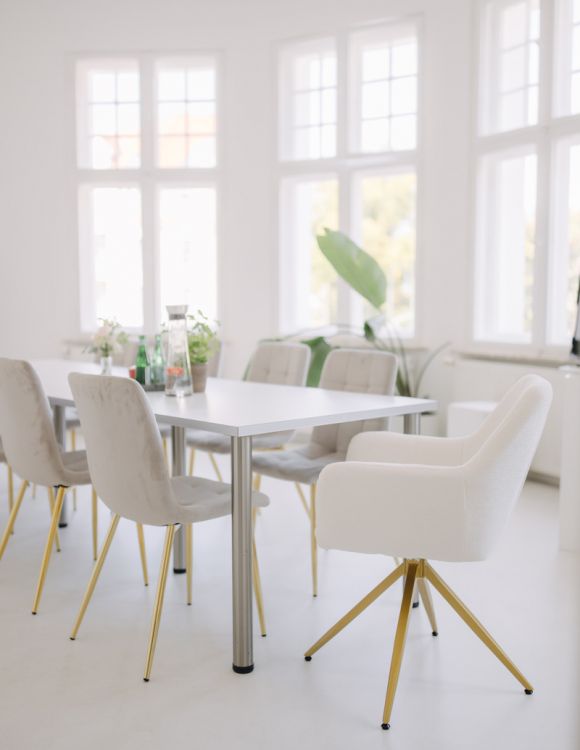 Helles, modernes Besprechungszimmer mit großen Fenstern, stilvollen Stühlen und dekorativen Pflanzen für eine angenehme Atmosphäre.