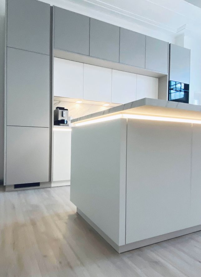 Moderne Einbauküche mit minimalistischem Design, heller Arbeitsfläche, LED-Beleuchtung und glatten Fronten für eine stilvolle Optik.